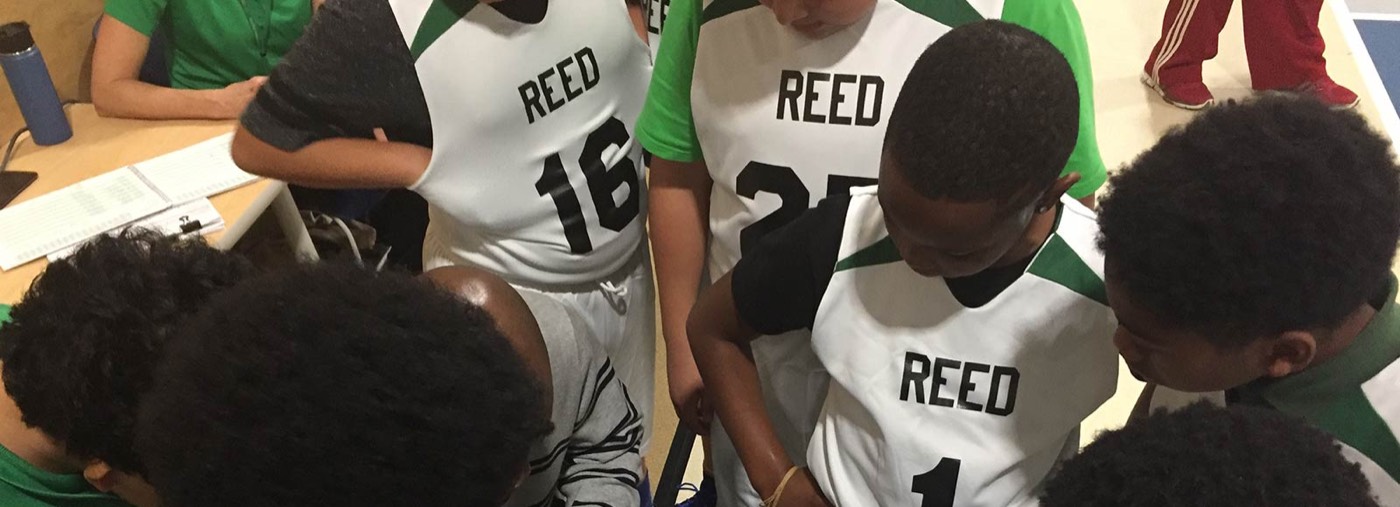 Marie Reed basketball team huddled together in Reed jerseys